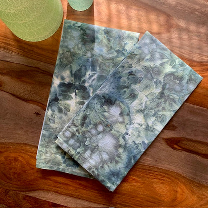 Two teal blue marble-patterned tea towels on a wooden surface