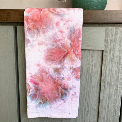 Colorful abstract patterned towel in pink tones hanging on a wooden cabinet.