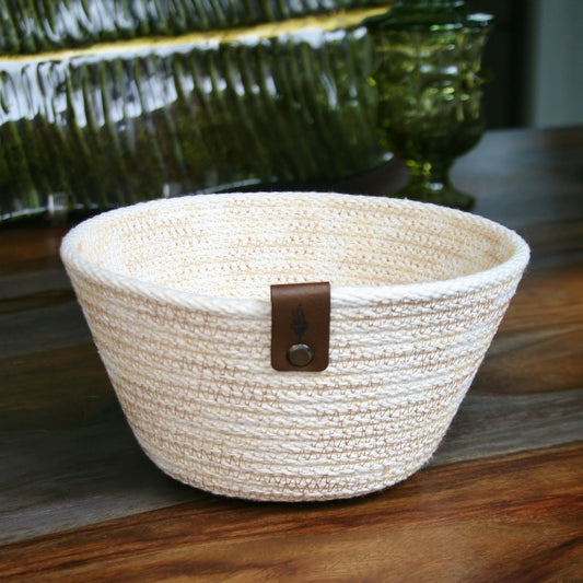 a sand-colored cotton rope basket set on a wood grain table 
