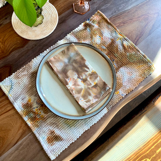 Hand-dyed woven cotton placemats and napkin from Astilbe Lane, shown in flat lay style.