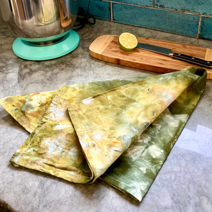 Hand-dyed green tea towel from Astilbe Lane, shown on kitchen counter.