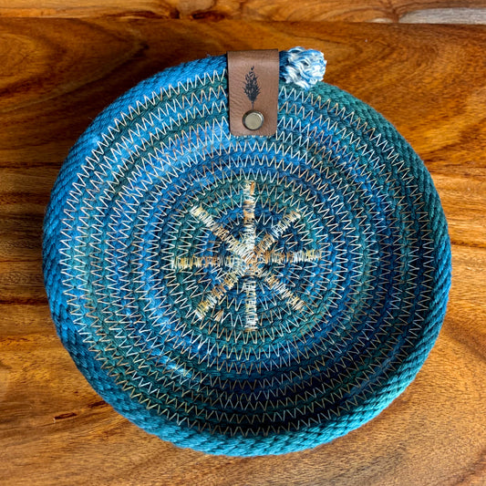 Small hand-dyed blue rope basket from Astile Lane, shown on woodgrain surface.