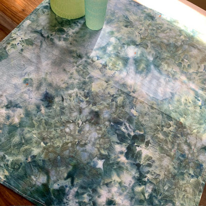 Marble-patterned kitchen towel with a green cup on a wooden table.