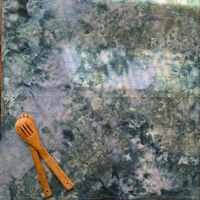 Wooden spatula and spoon on a teal-blue marble tea towel 